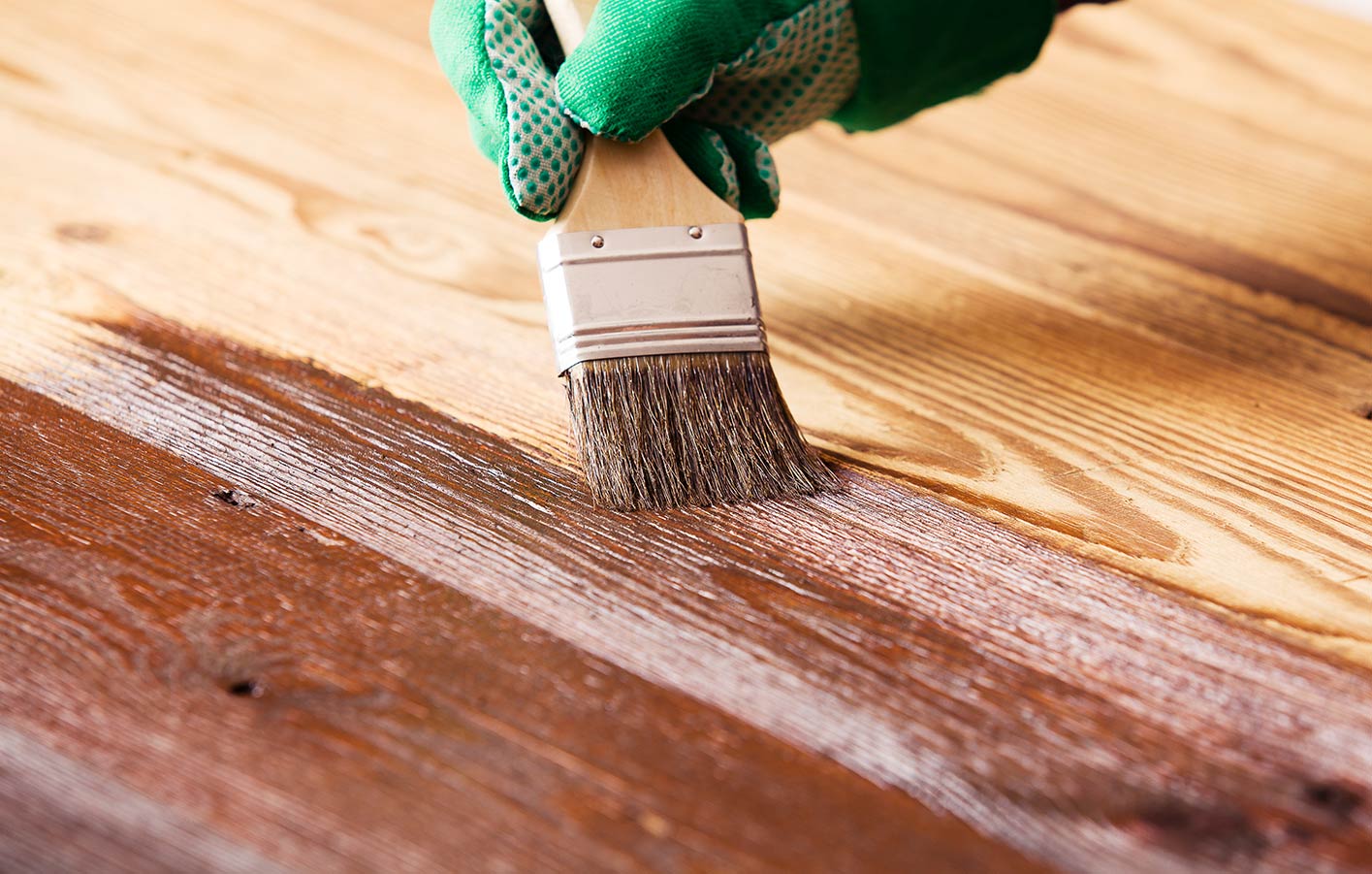 Pinsel trägt Lasur auf Holz auf 